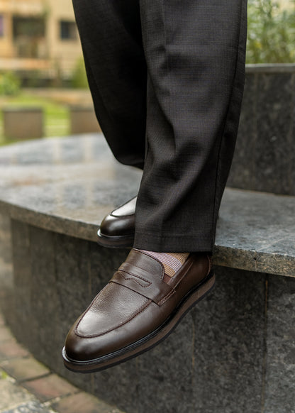 Brown leather shoes worn with dark trousers on a stone step.