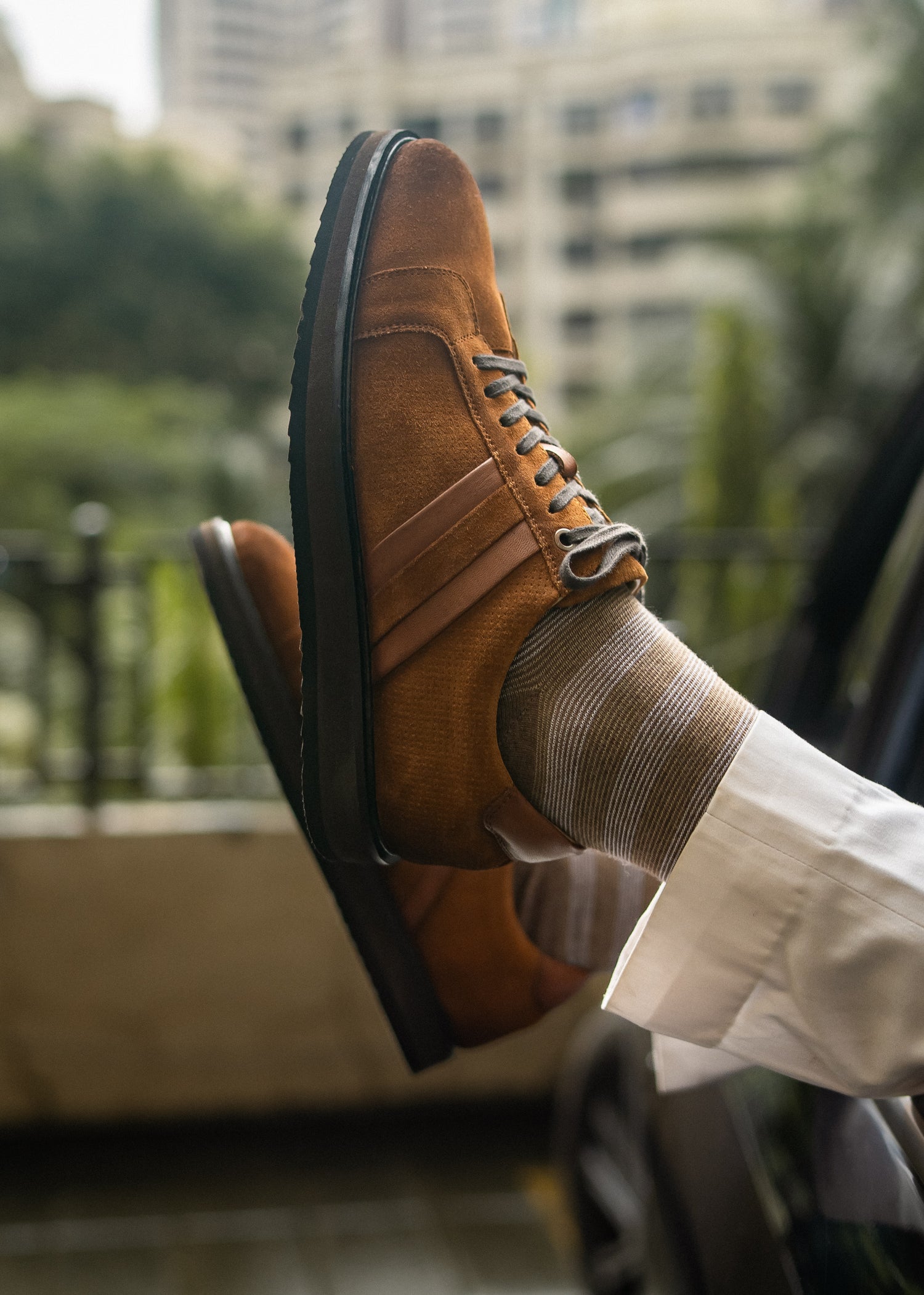 Brown leather shoe with a blurred cityscape background